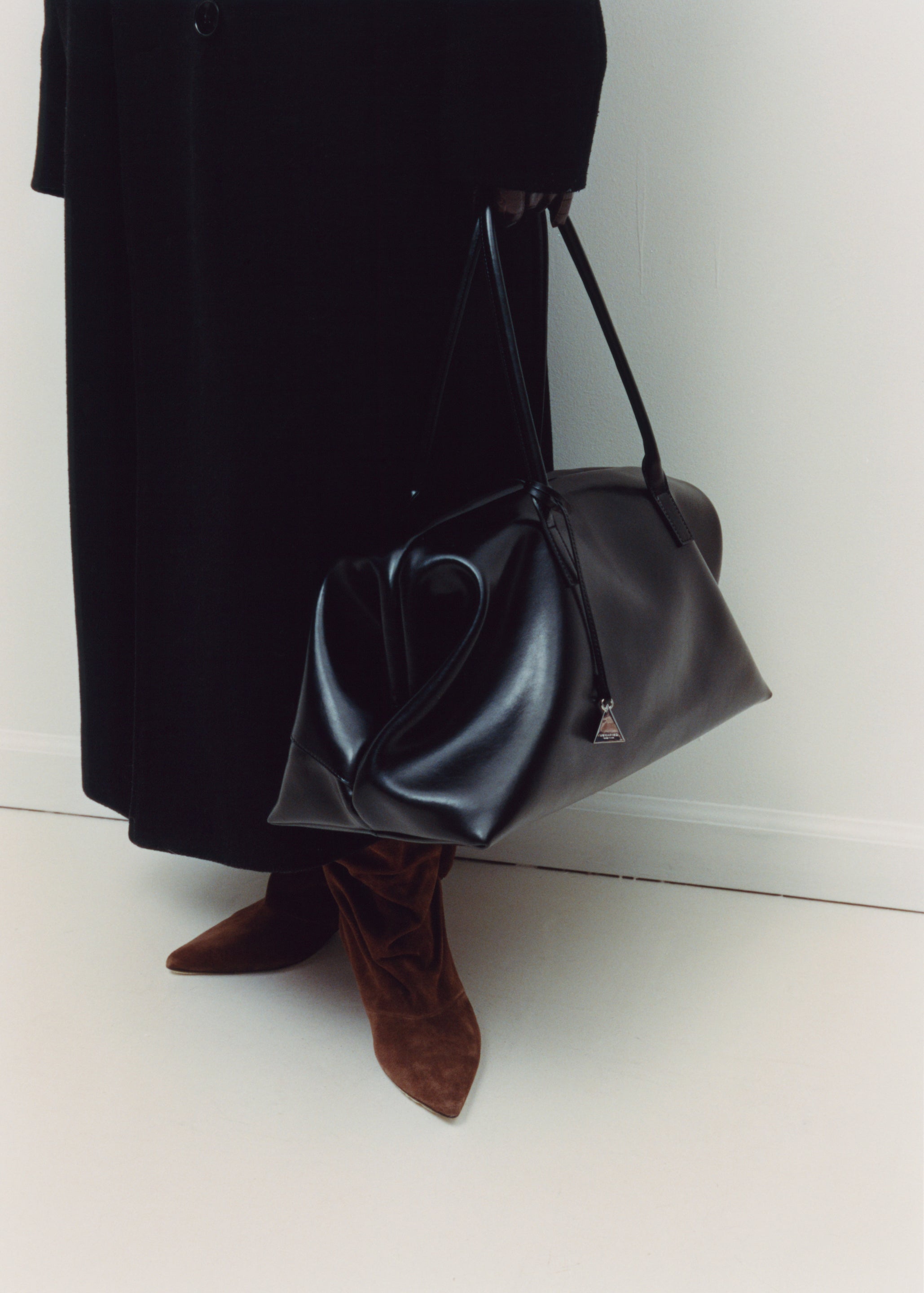Person holding a Black Club Large Handbag with a plain background