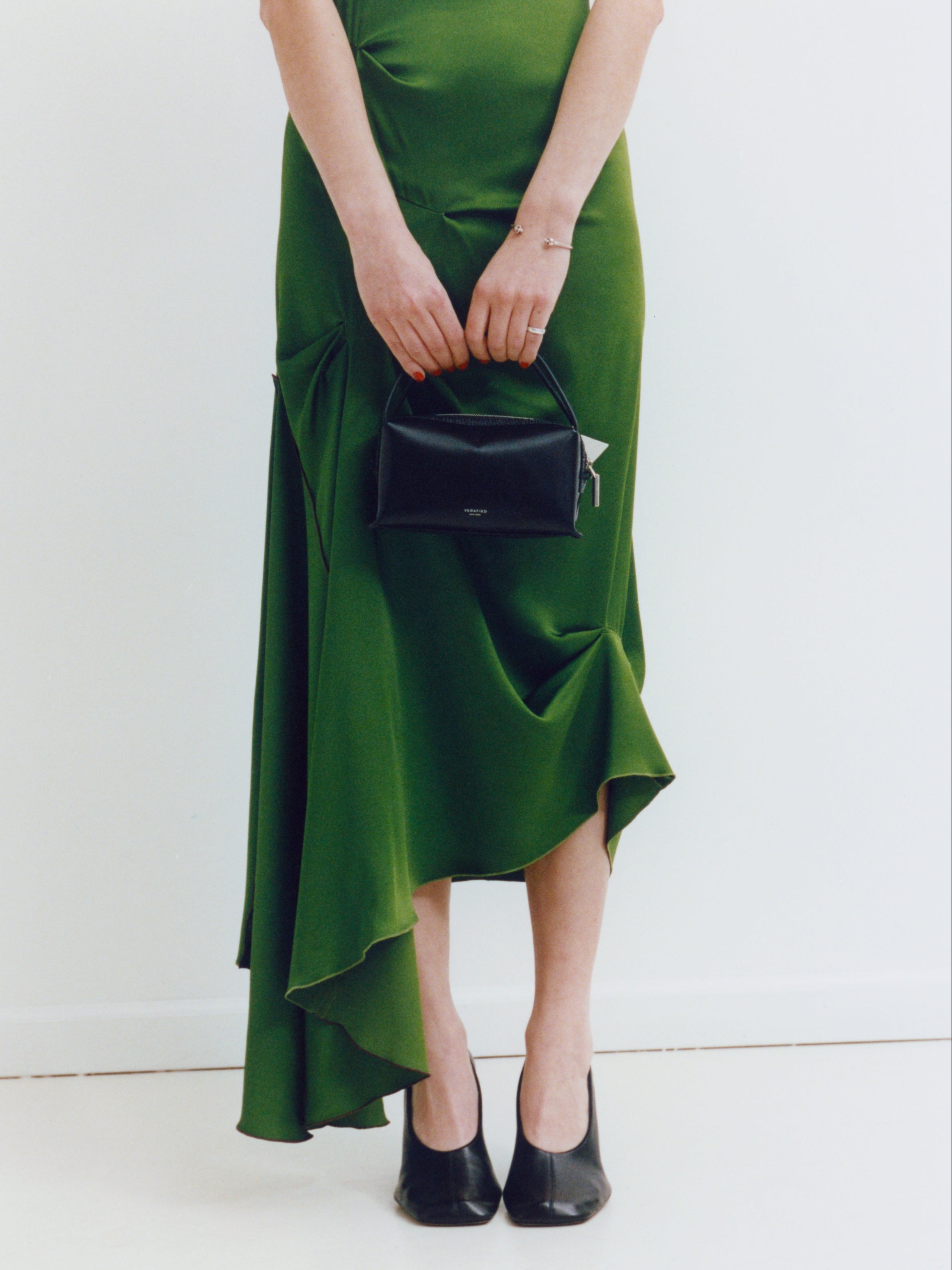 Person wearing a green dress holding a Black Lizard Café Mini Handbag on a white background