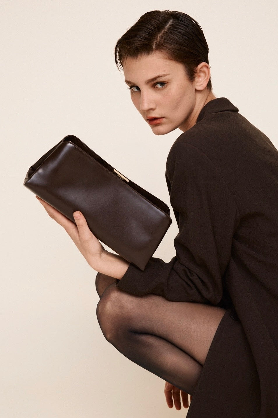 Woman holding a Chocolate Éclair Clutch Shoulder Handbag against a plain background