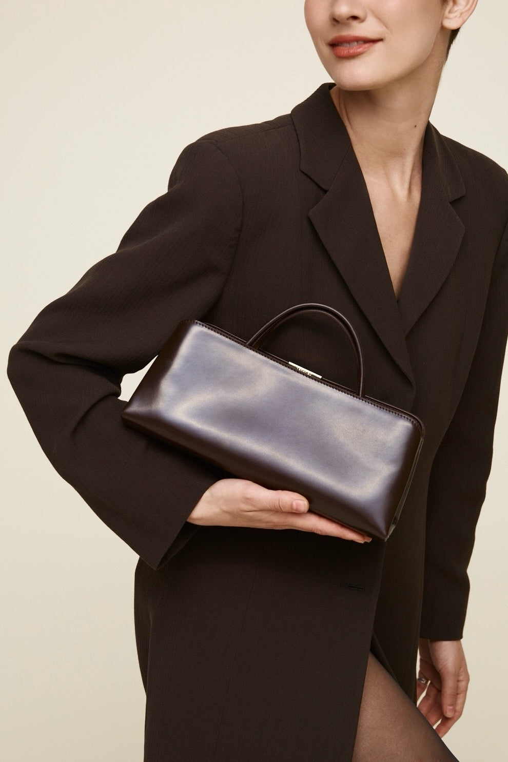 Woman holding a Chocolate Éclair Clutch Shoulder handbag against a neutral background