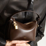 A person holding a Mini Gold Chocolate Hobo Shoulder Handbag