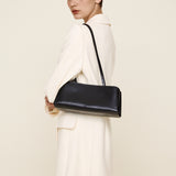 Woman holding a Silver Noir Éclair Clutch Shoulder Handbag (Black) against a plain background