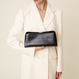 Woman holding a Silver Noir Éclair Clutch Shoulder Handbag (Black) against a plain background