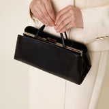 Person holding a Silver Noir Éclair Clutch Shoulder Handbag (Black) with a white coat