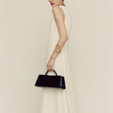 Woman in a long white dress holding a Gold Noir Éclair Clutch Shoulder Handbag (Black) against a plain background