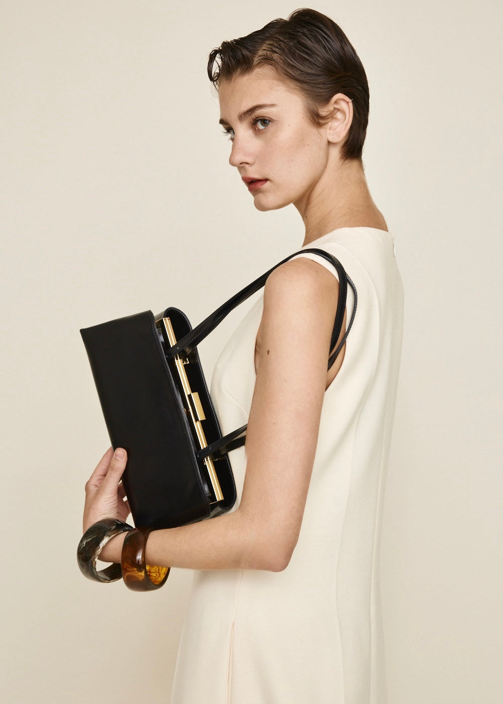Woman holding a Gold Noir Éclair Clutch Shoulder Handbag (Black) against a plain background