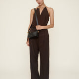 Woman wearing a brown jumpsuit holding a Mini Gold Black Hobo Shoulder Handbag on a white background