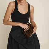 Woman holding a Chocolate Circle Ring Mini Handle Bag against a beige background
