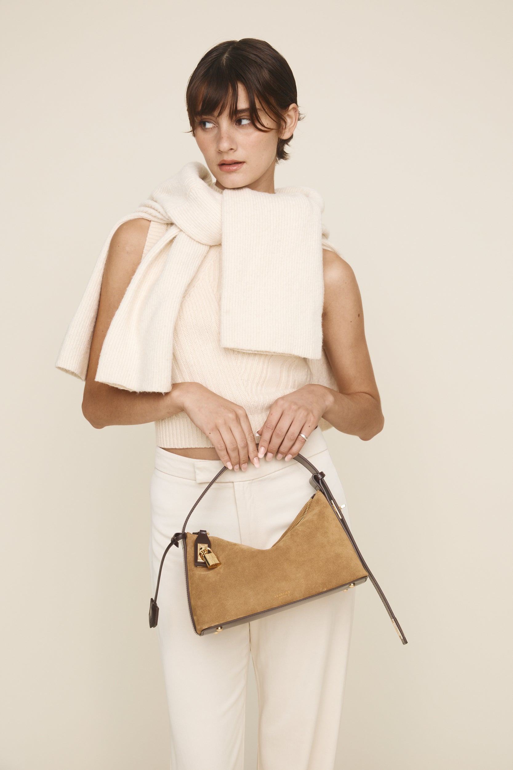 Woman holding a beige Gold Suede Hobo Shoulder Handbag against a plain background