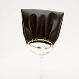 Black cocktail glass with a Chocolate Circle Ring Mini Handle Bag on a white background