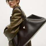 Person wearing a green coat holding a large Chocolate Club Large Handbag against a white background