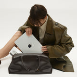 Person holding a laptop next to a Chocolate Club Large Handbag on a white background