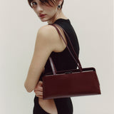 Woman holding a Burgundy Clutch Shoulder Handbag against a plain background