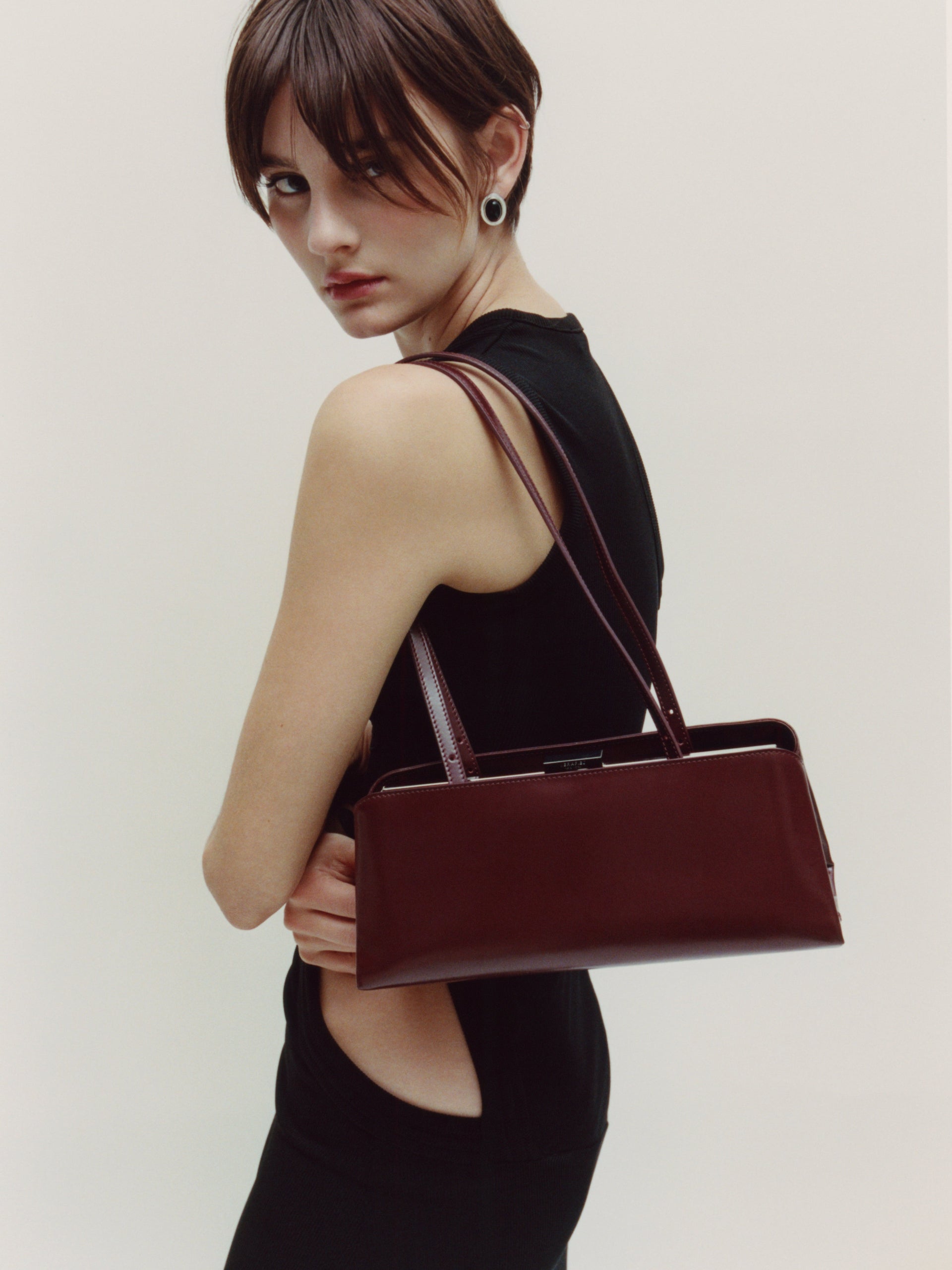 Woman holding a Burgundy Clutch Shoulder Handbag against a plain background