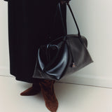 Person holding a Black Club Large Handbag with a plain background