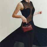 Woman holding a Maroon Python Café Mini Bag: Crossbody Handbag wearing a black dress with a heart design.