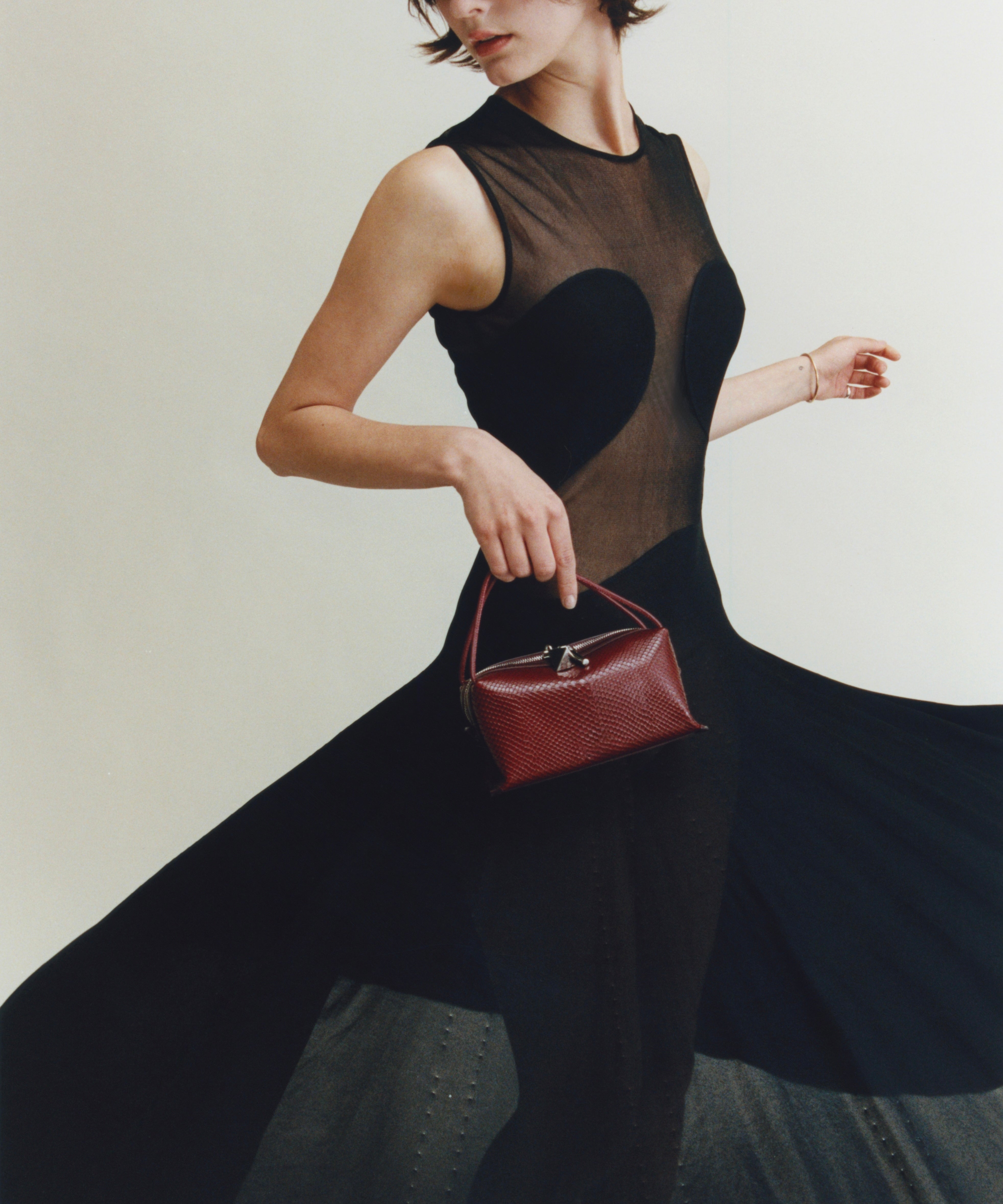 Woman holding a Maroon Python Café Mini Bag: Crossbody Handbag wearing a black dress with a heart design.