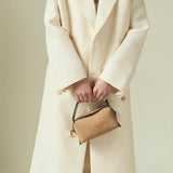 Person wearing a long cream coat holding a Verafied New York Gold Suede Café Mini Handbag against a neutral background
