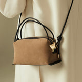Verafied New York Gold Suede Café Mini Handbag with black strap held by a person wearing a beige coat.