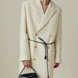 Person wearing a long cream coat with a black belt, holding a Verafied New York Black Lizard Café Mini Handbag against a neutral background.