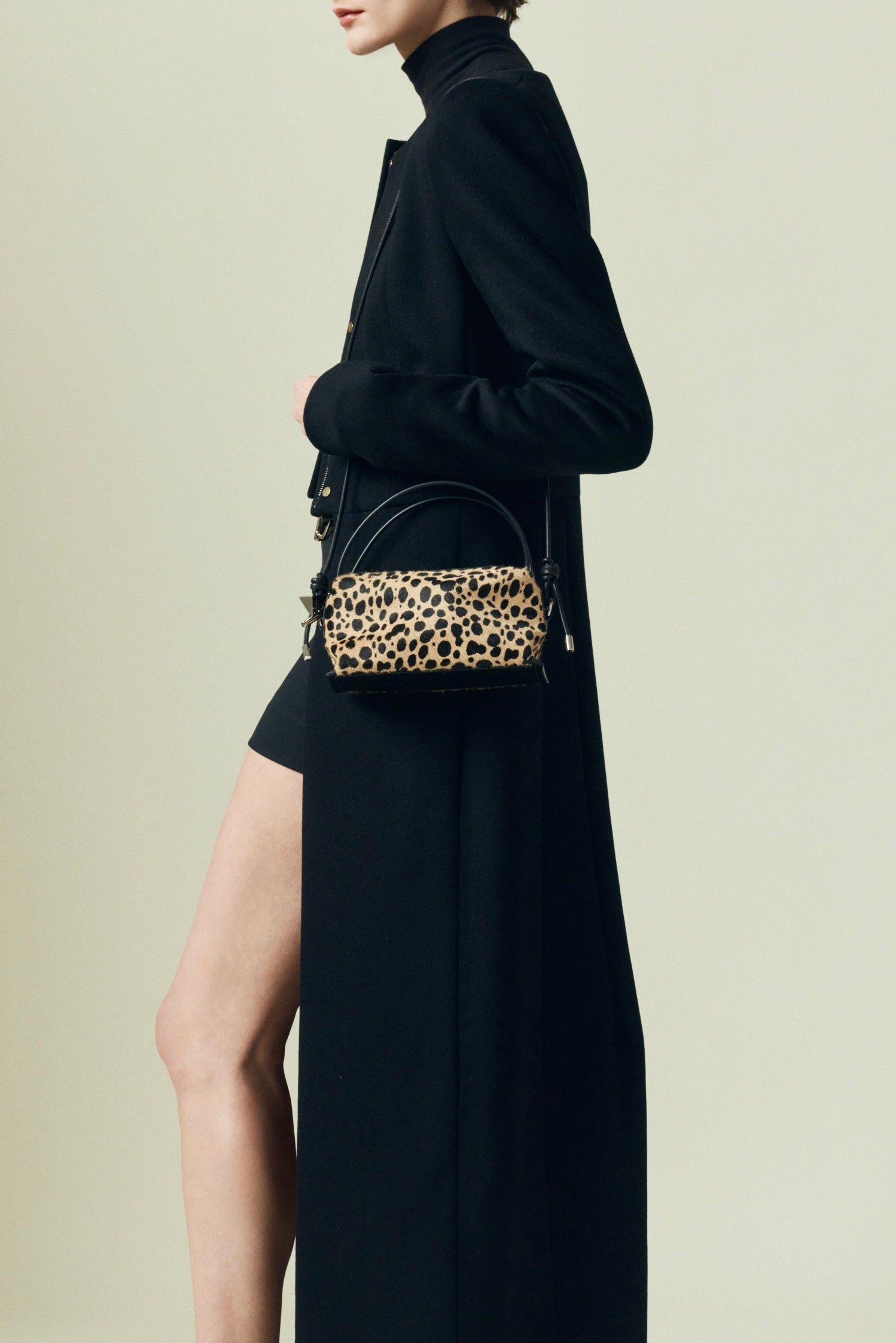 Person wearing a black outfit with a leopard print Verafied New York Cheetah Calf Hair Café Mini Handbag on a beige background