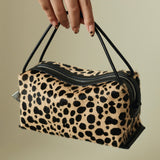 Leopard print Verafied New York Cheetah Calf Hair Café Mini Handbag held by a hand against a beige background