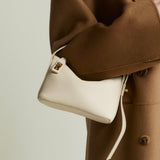 Person wearing a brown coat holding a white Ivory Twister Hobo Handbag against a neutral background