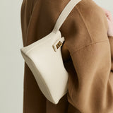 Person wearing a brown coat with a white Ivory Twister Hobo Handbag on a plain background