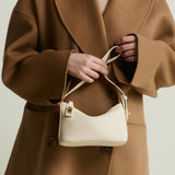 Person wearing a brown coat holding a Ivory Twister Hobo Handbag against a neutral background