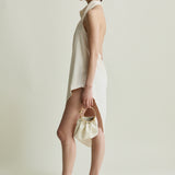 Woman in a white dress holding a Cream Circle Ring Handle Bag against a plain background