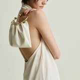 Woman wearing a white dress with a Cream Circle Ring Handle Bag on a plain background