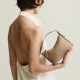 Woman holding a beige Twister Hobo Shoulder Handbag against a plain background