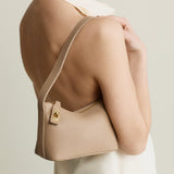 Beige Twister Hobo Shoulder Handbag worn over shoulder on a plain background