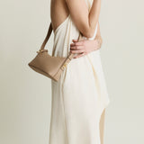 Woman holding a beige Twister Hobo Shoulder Handbag against a plain background