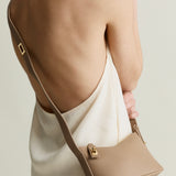 Beige Twister Hobo Shoulder Handbag held by a person wearing a beige coat against a neutral background