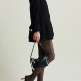 Person wearing a black outfit with a Mini Silver Black Hobo Shoulder Handbag on a plain background