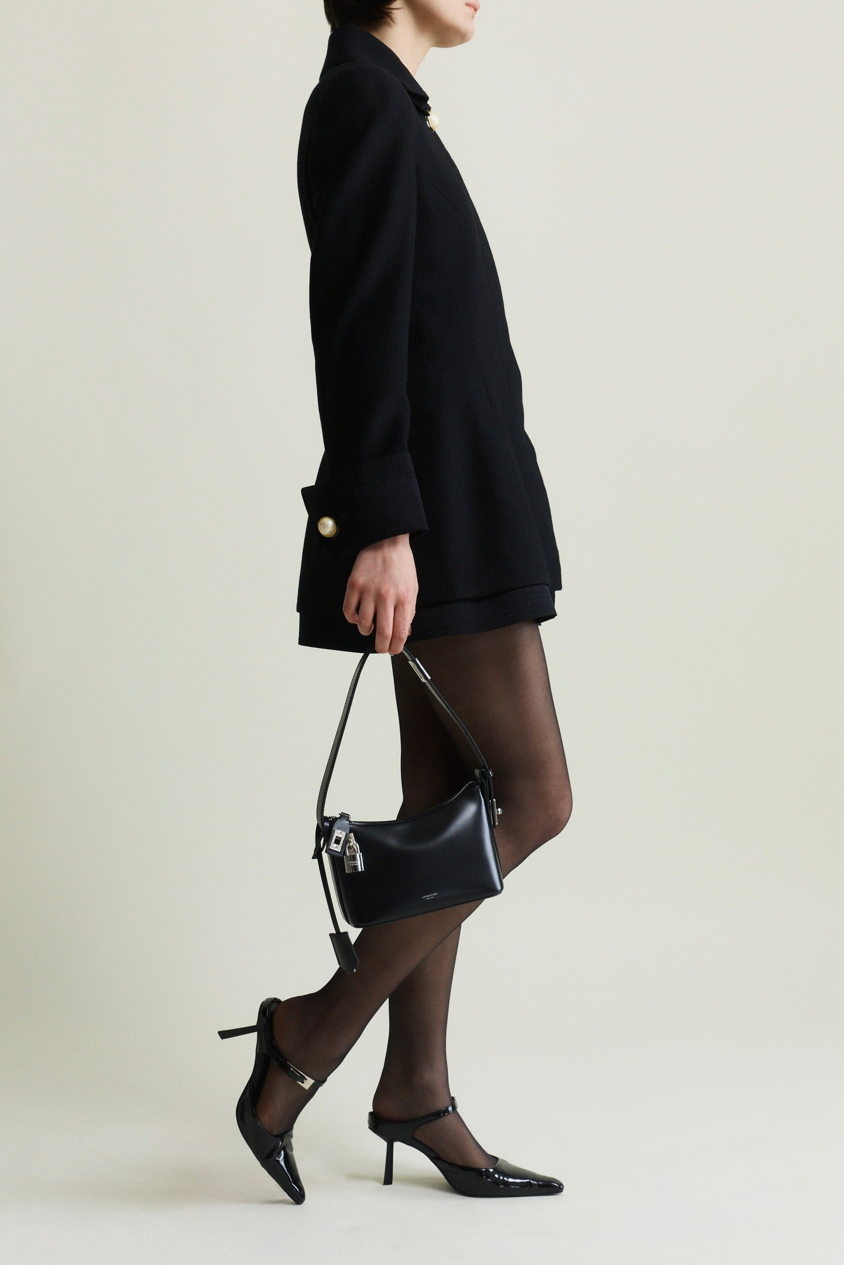 Person wearing a black outfit with a Mini Silver Black Hobo Shoulder Handbag on a plain background