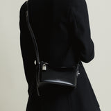 Person wearing a black coat with a Mini Silver Black Hobo Shoulder Handbag on a plain background