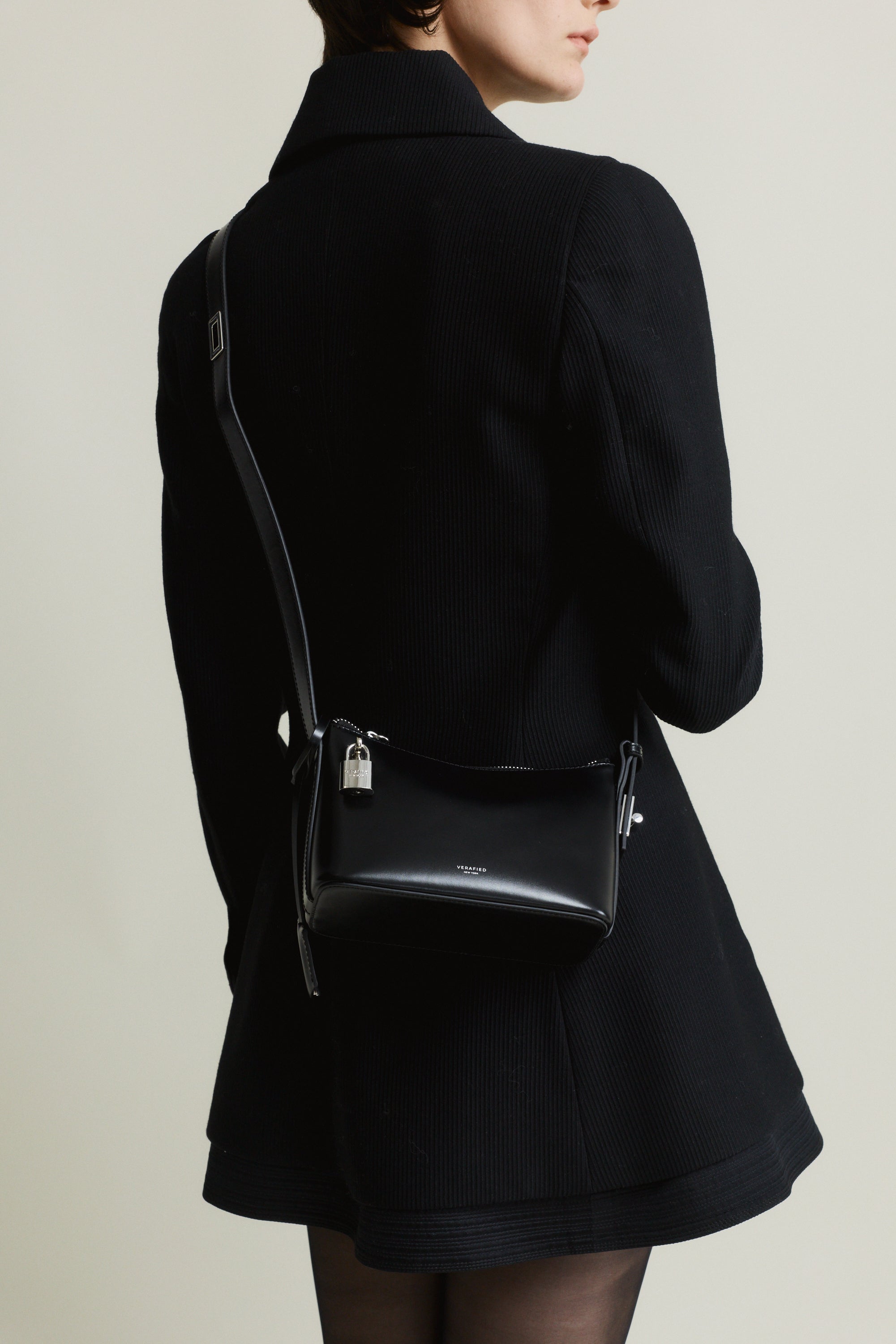Person wearing a black coat with a Mini Silver Black Hobo Shoulder Handbag on a plain background