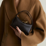 Person wearing a brown coat holding a Chocolate Café Mini Crossbody Handbag against a neutral background