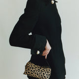 Person wearing a black dress holding a leopard print Cheetah Calf Hair Café Mini Crossbody Handbag against a plain background