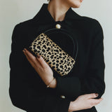 Person wearing a black outfit with a leopard print Cheetah Calf Hair Café Mini Crossbody Handbag on a plain background