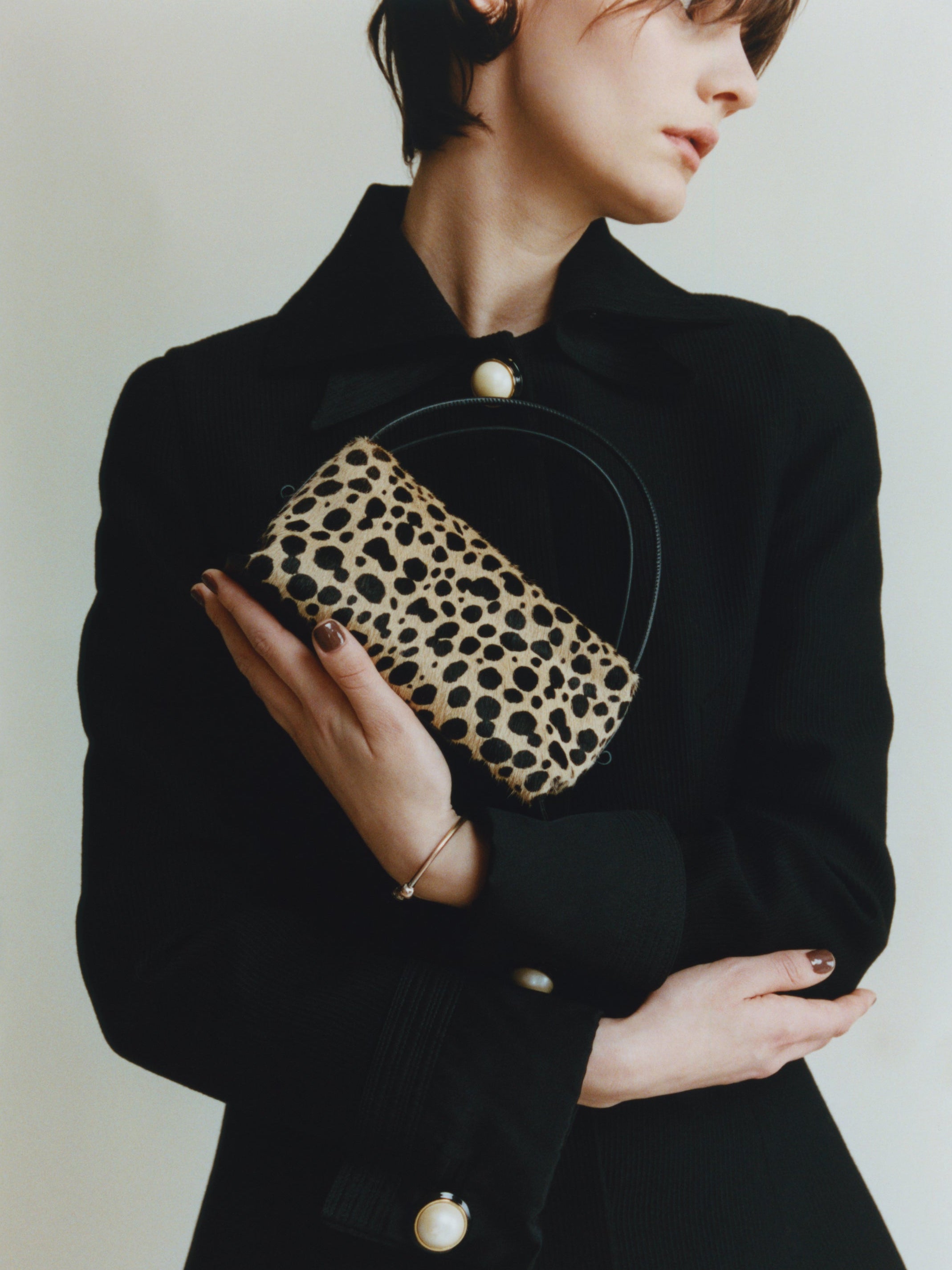 Person wearing a black outfit with a leopard print Cheetah Calf Hair Café Mini Crossbody Handbag on a plain background