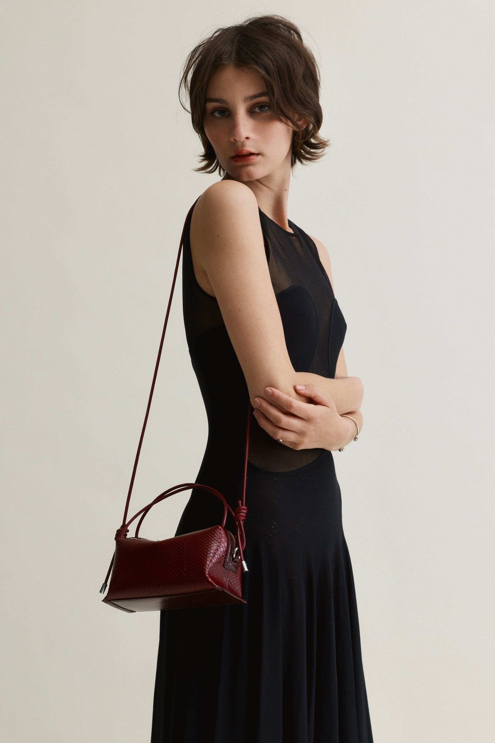 Woman holding a Maroon Python Café Mini Bag: Crossbody Handbag against a plain background