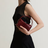 Woman holding a Maroon Python Café Mini Bag: Crossbody Handbag against a plain background