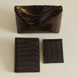 Set of brown leather pouches and Mocha Croc Embossed Passport Cover Wallet on a beige background