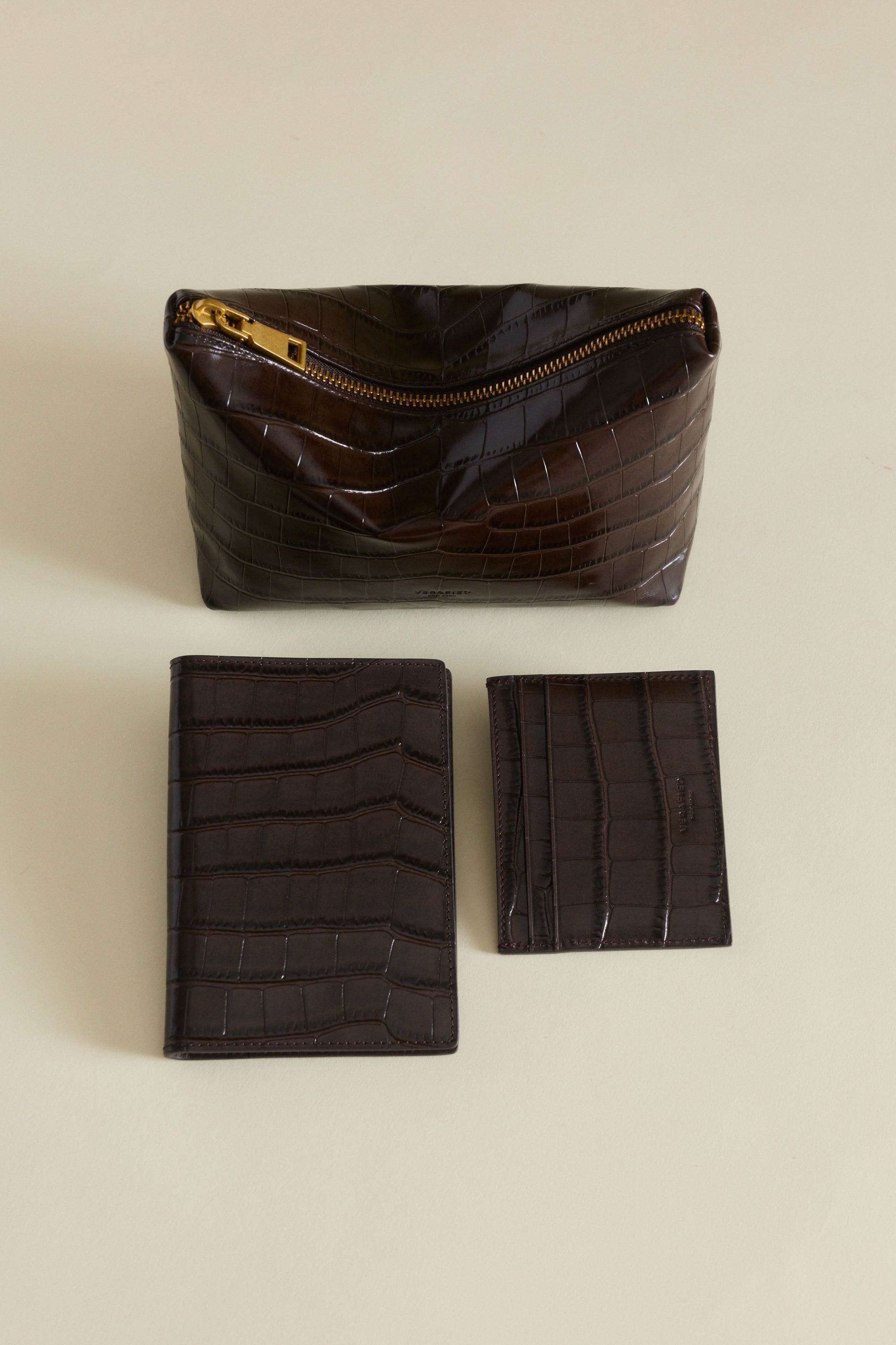 Set of brown leather pouches and Mocha Croc Embossed Passport Cover Wallet on a beige background
