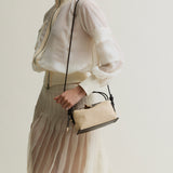 Woman holding a Raffia Café Mini Crossbody Handbag against a plain background