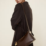 Woman wearing a dark coat with a Gold Chocolate Hobo Shoulder Handbag on a plain background