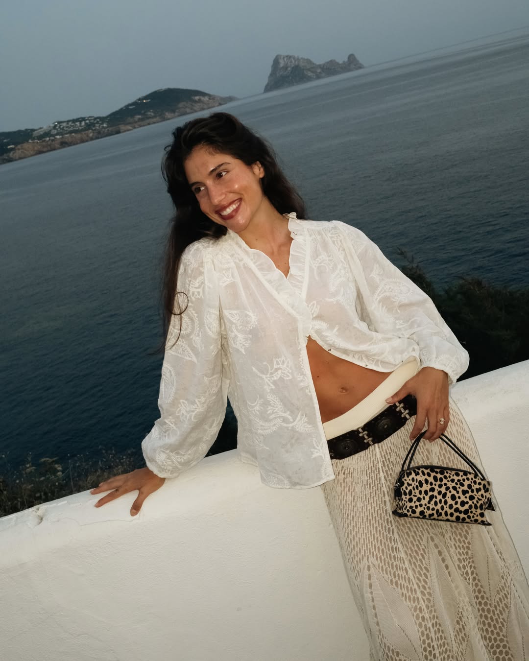 Woman in a white outfit with a leopard print Cheetah Calf Hair Café Mini Crossbody Handbag by the sea